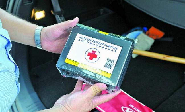 Новая запечатанная автомобильная аптечка Человек держит в руках аптечку