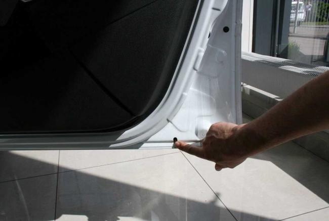 Дренажное отверстие в двери автомобиля Человек указывает на дренажное отверстие в автомобиле