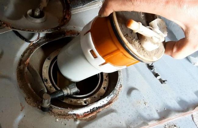 Замена бензонасоса в автомобиле Человек вытаскивает топливный насос