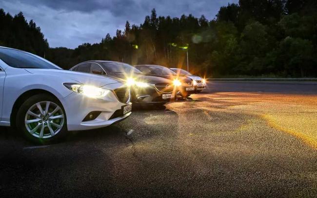 Включенные фары у автомобилей Машины стоят в ряд с включенными фарами