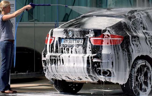 Мойка машины для подготовки к консервации Девушка моет машину