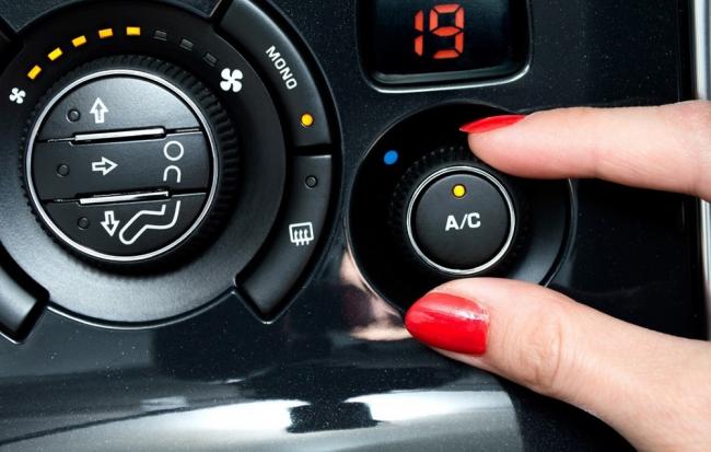 Включение кондиционера в машине Девушка включает кондиционер в автомобиле