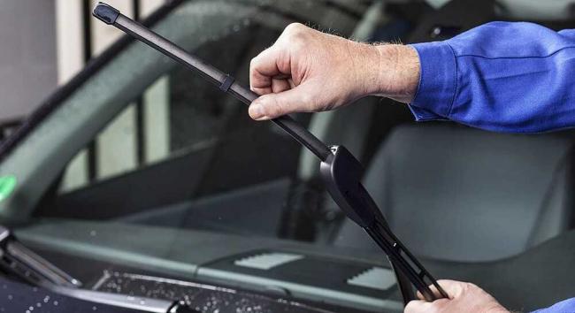 Мастер осматривает дворники автомобиля Дворники автомобиля в руках мастера