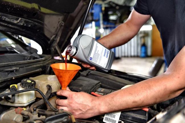 Доливка моторного масла Мастер доливает масло через лейку