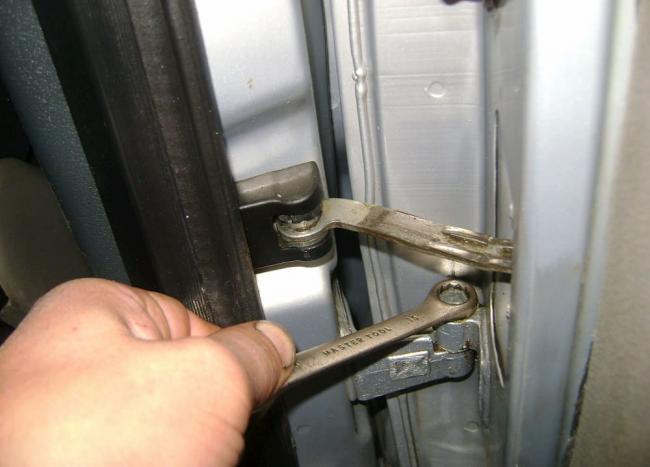 Регулировка петель у дверей машины Мастер регулирует петли автомобиля