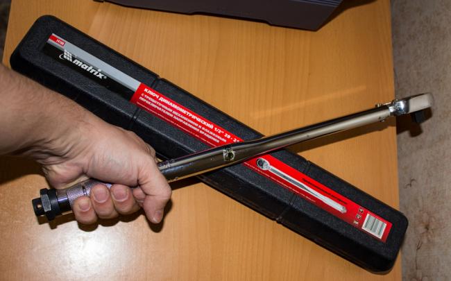 Мужчина держит в руке динамометрический ключ Мужчина держит в руке динамометрический ключ