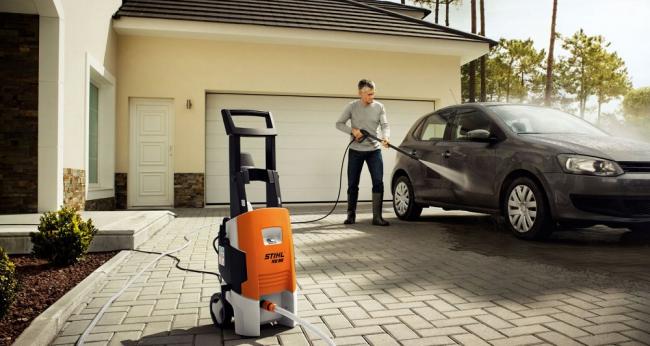 Двор частного дома, где человек моет машину Мужчина моет машину во дворе частного дома