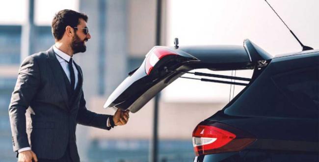 Мужчина закрывает багажник автомобиля Мужчина придерживает крышку багажника