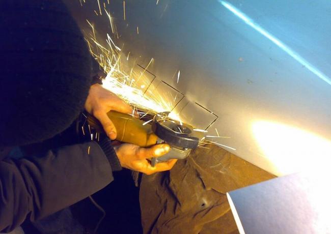 Резка болгаркой по разметке Мужчина режет капот болгаркой