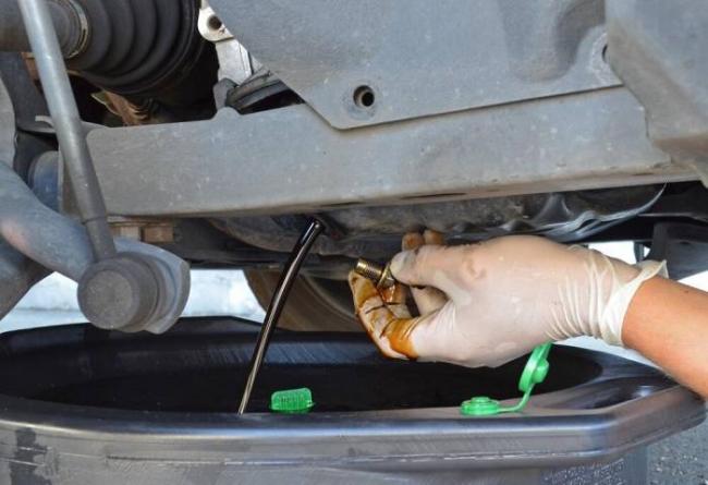 Слив старого машинного масла Мужчина сливает моторное масло