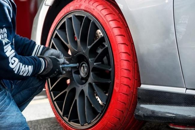 Мастер меняет колеса в автомобиле Мужчина ставит колеса на машину