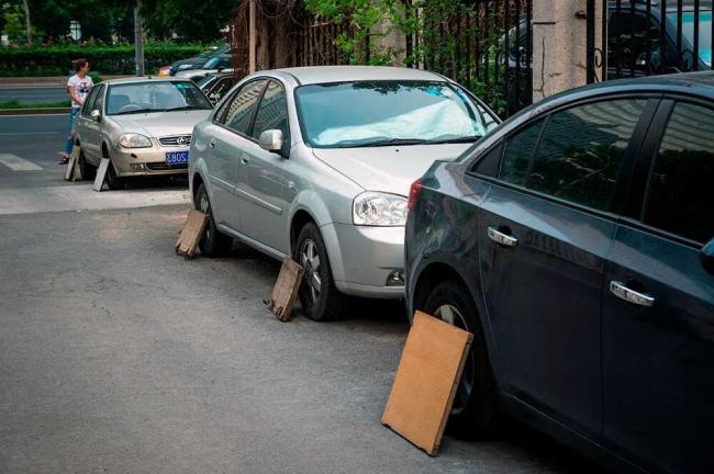 Дощечки на колесах припаркованных машин Три машины с дощечками на колесах