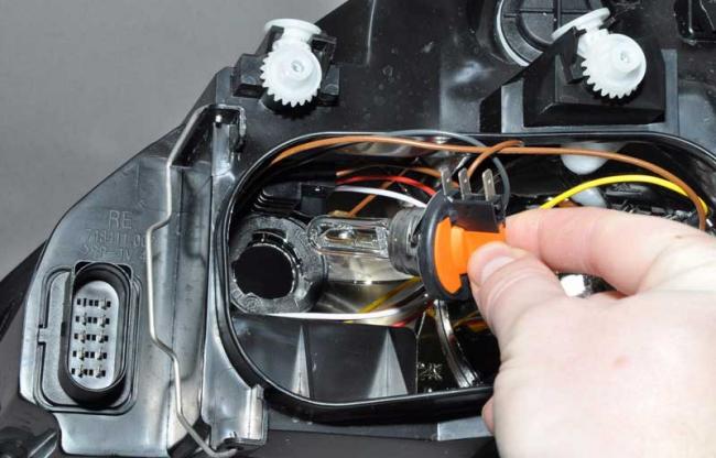 Процесс замены лампочки в передней фаре машины Замена лампочки в передней фаре автомобиля